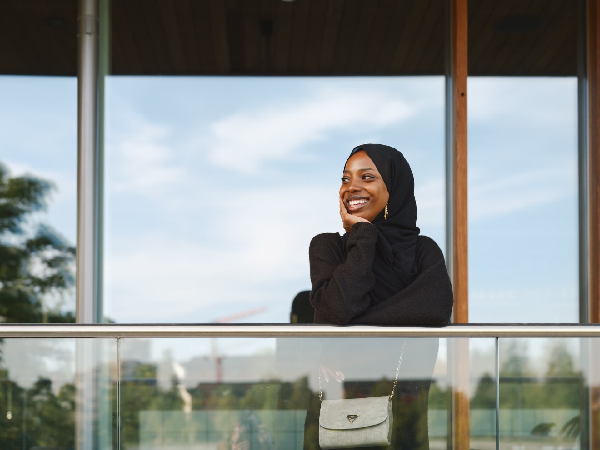 Kvinna i hijab vid balkong och modern arkitektur