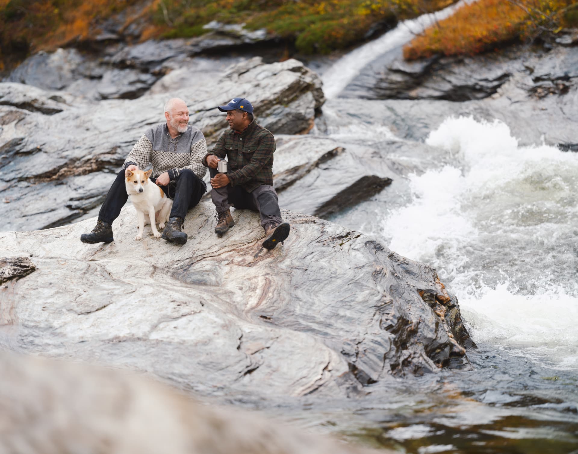 Två män och en hund vid ett vattenfall